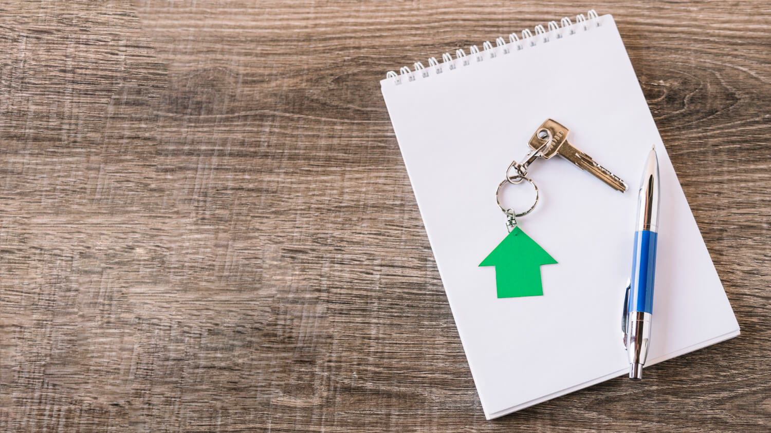 clé de maison sur un carnet avec un stylo, illustrant le bail signé mais pas de remise de clés