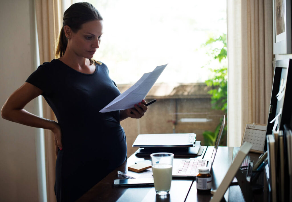 Femme enceinte rédigeant sa lettre de congé pour une location, cherchant à savoir si la grossesse permet une réduction du préavis.