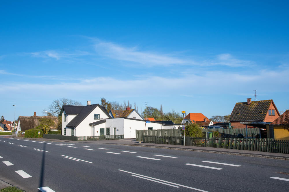 Bruit d'autoroute à 300m : quel est l'impact réel et quelles solutions ? 1 Vue d'une maison avec jardin, avec une autoroute visible à 300m à l'horizon, illustrant la proximité.