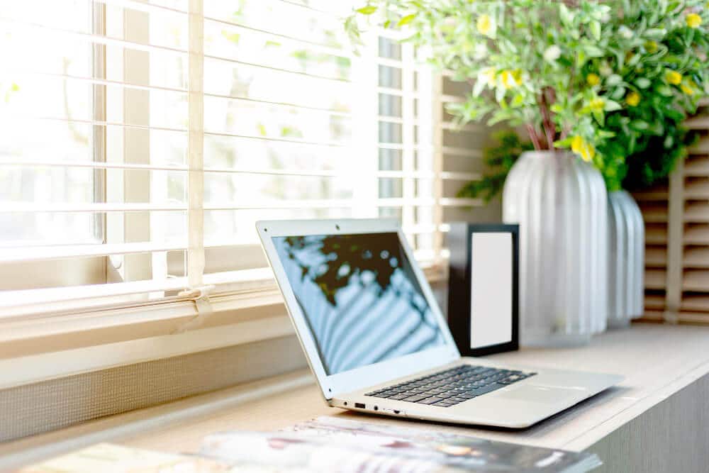 Vue depuis la grande fenêtre d'un appartement exposé nord, montrant une lumière douce et constante sur un coin bureau.