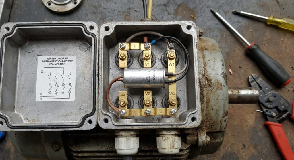 Branchement d'un condensateur permanent sur la plaque à bornes d'un moteur asynchrone triphasé