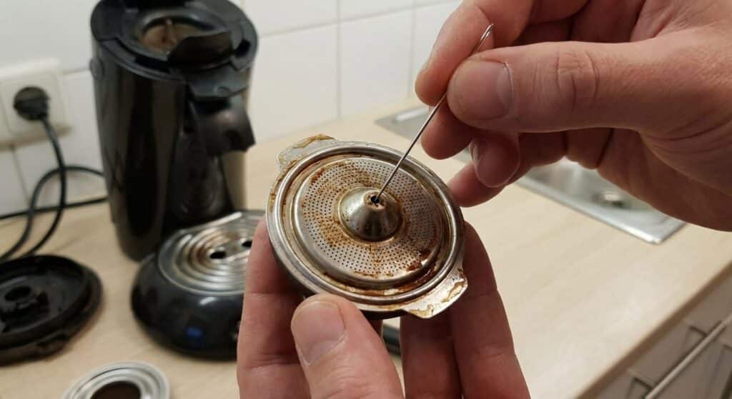Débouchage du filtre central du porte-dosette d'une machine Senseo avec une aiguille