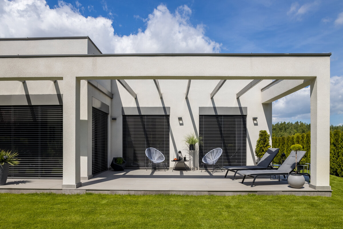 Une pergola bioclimatique en aluminium sur mesure installée sur la terrasse ensoleillée d'une maison contemporaine.