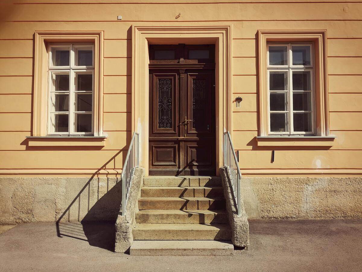 Une porte d'entrée moderne en chêne massif avec double vitrage sablé installée sur la façade d'une maison.