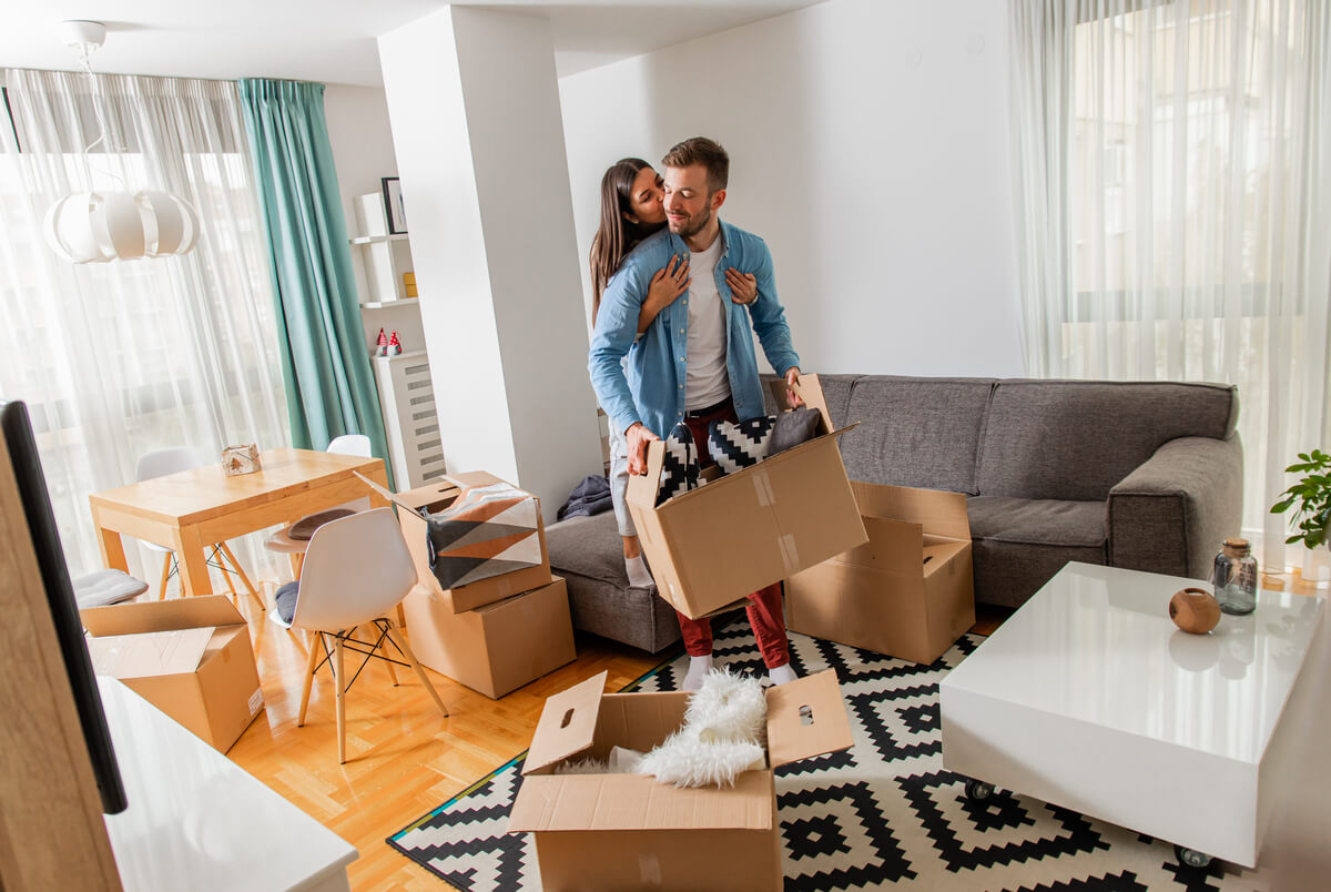 Un couple déballant des cartons dans son nouvel appartement en Suisse, illustrant le début de la période de 14 jours.