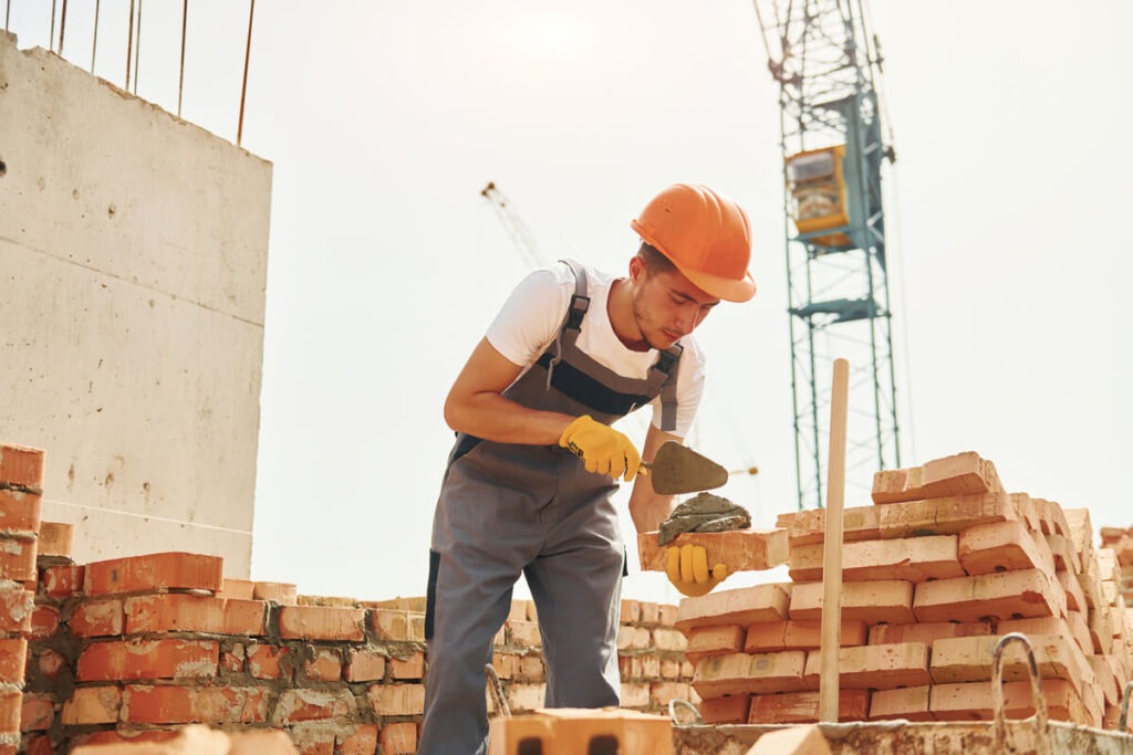 Quel artisan BTP a besoin d'une garantie décennale en auto-entrepreneur ? 3 Un maçon auto-entrepreneur travaillant sur un chantier de construction, une activité soumise à la décennale obligatoire.