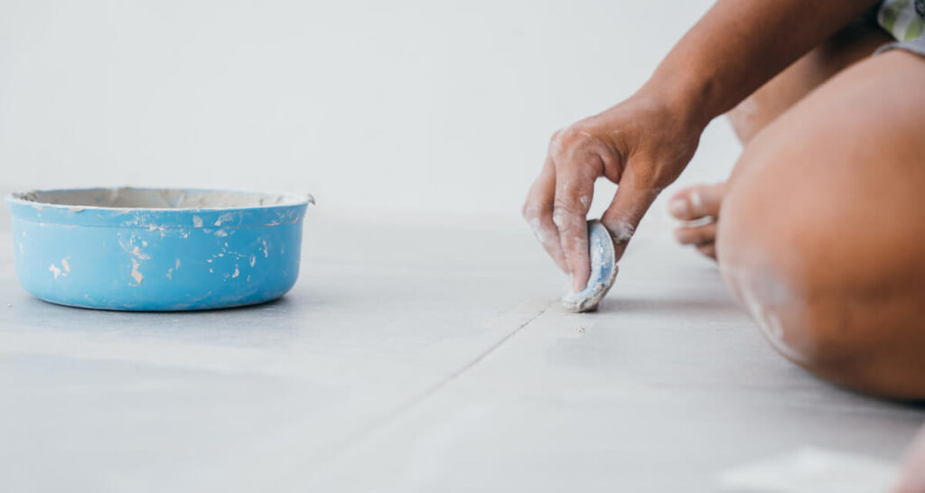 Rénovation des joints à l'aide d'un stylo de coloration blanc sur un carrelage de cuisine sombre.