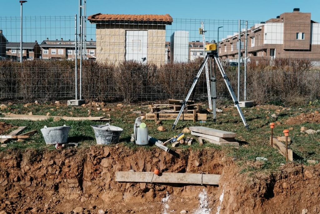 Peut-on construire une dalle de piscine sur une fosse septique ? 2 Un géomètre délimitant la zone d'implantation d'une piscine dans un jardin à distance des installations d'assainissement.