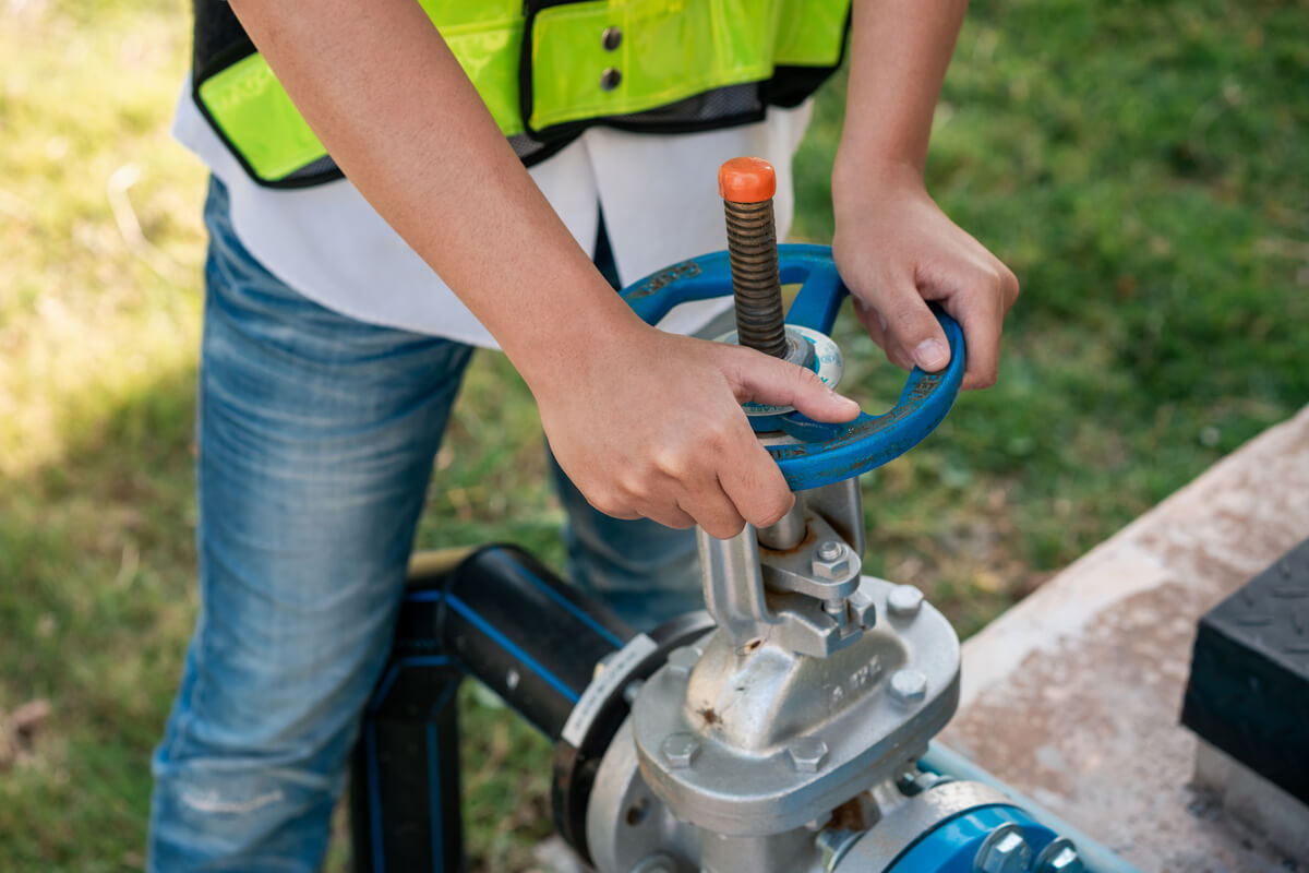Un usager vérifiant la vanne d'arrêt générale de son compteur d'eau Veolia dans son jardin.