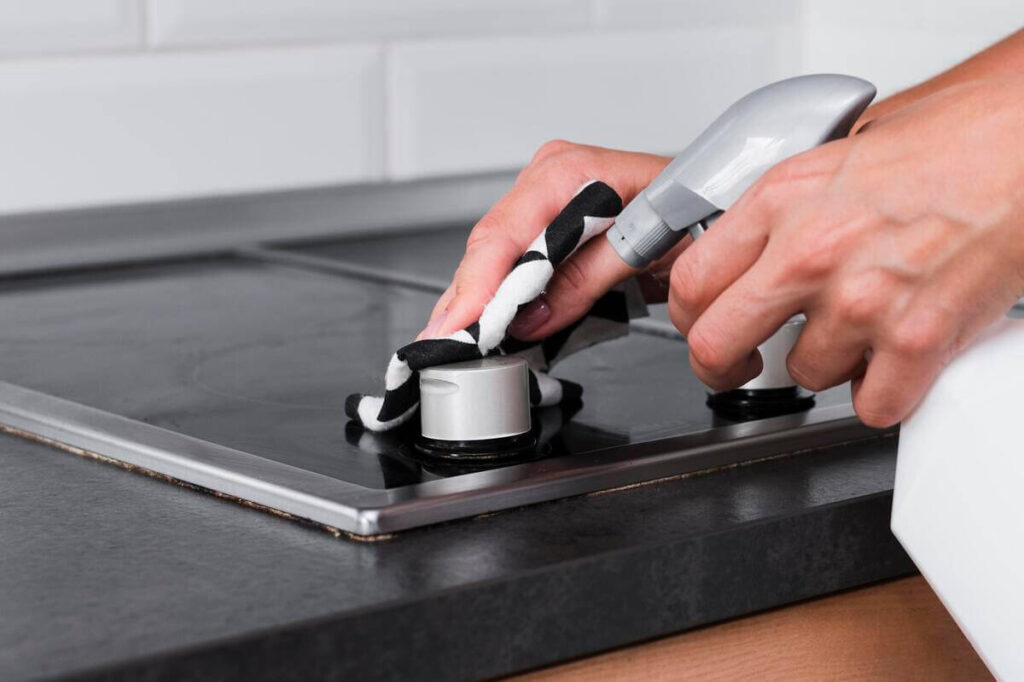 Une personne démontant les boutons rotatifs d'une table de cuisson pour éponger l'humidité accumulée.