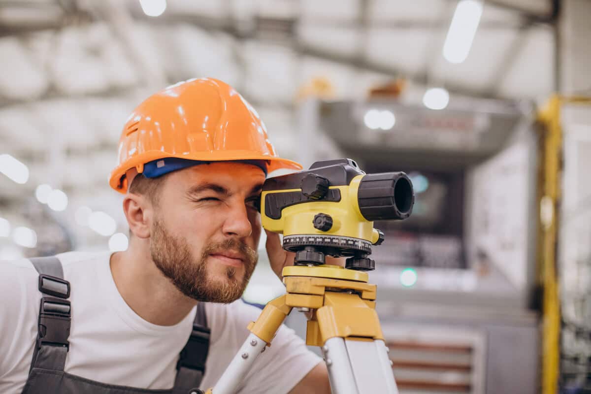 Géomètre mesurant la hauteur au faîtage d'une toiture de maison individuelle avec un télémètre laser.