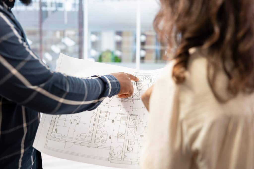 Maître d'œuvre en réunion sur un chantier de maison individuelle avec les plans d'architecte.