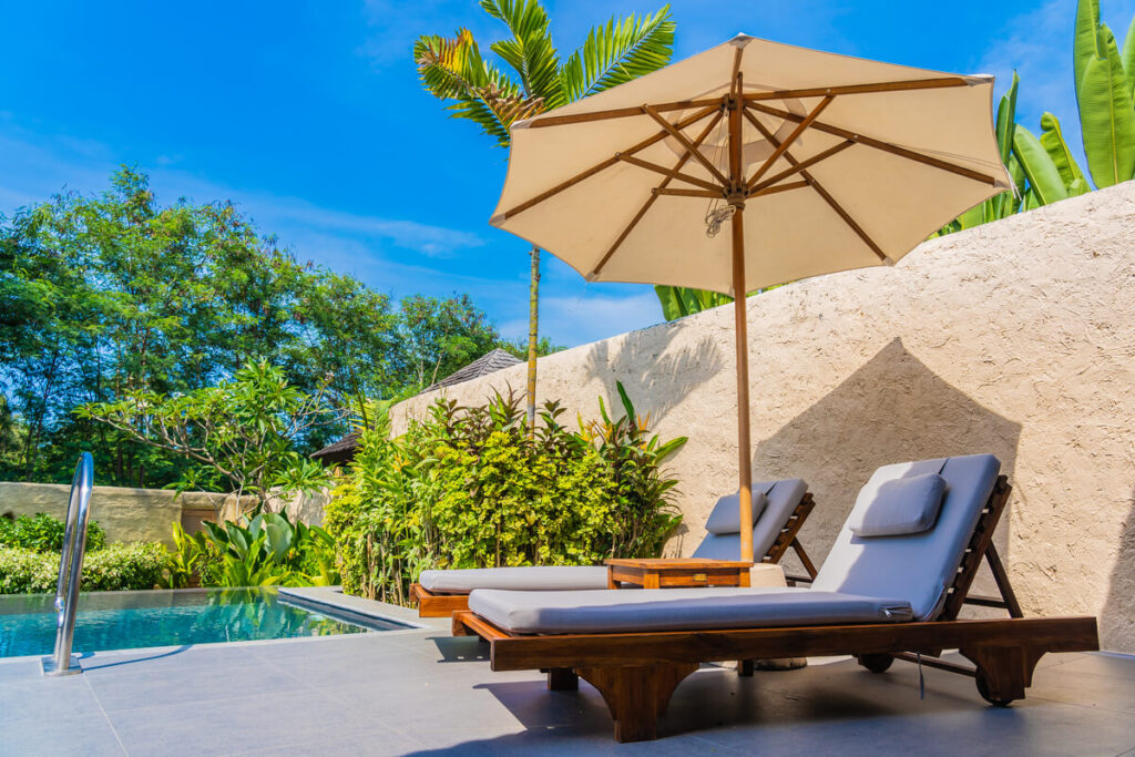 Coin détente moderne avec mobilier de jardin et parasol installé à proximité de la piscine.