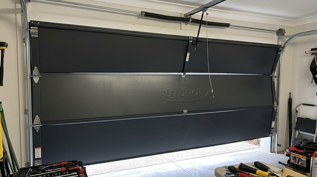 Porte de garage sectionnelle de marque Futurol bloquée à mi-course dans ses rails latéraux.
