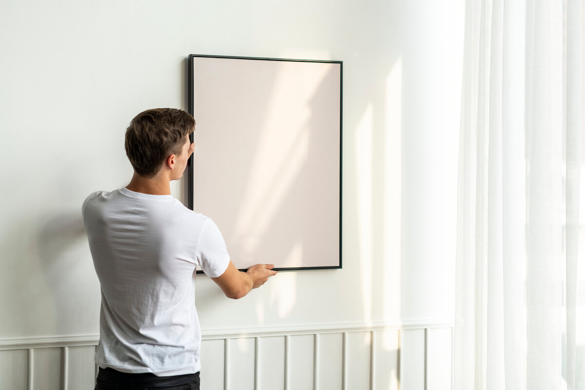 Cadre photo grand format avec tirage de paysage accroché sur un mur clair au-dessus d'un canapé contemporain.